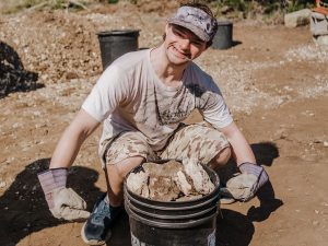 Man smiling picking up rocks proudly